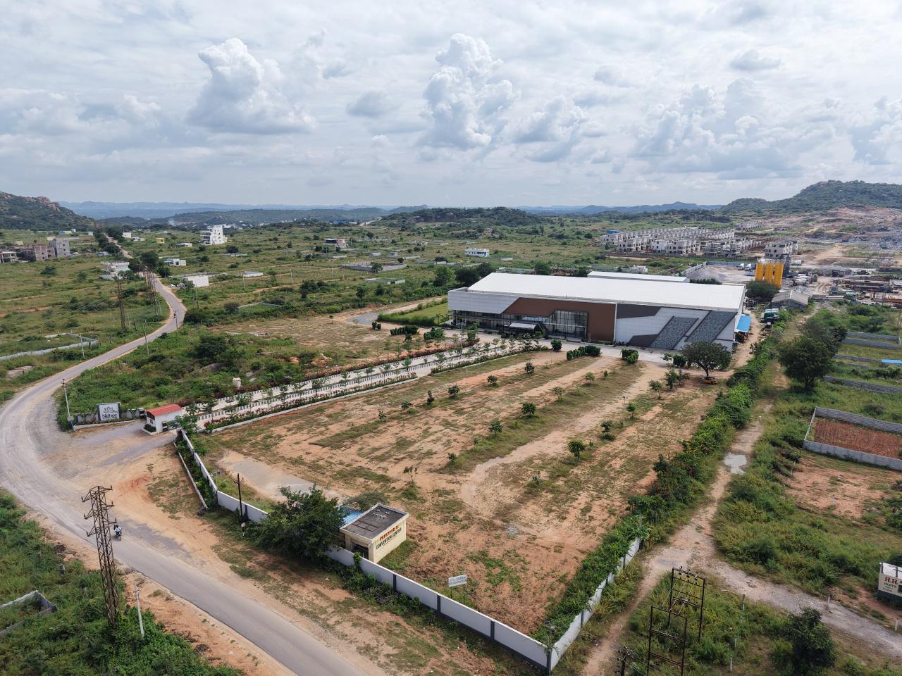 Angled aerial view showing Nidhee Convention Centre, approach road and surrounding grounds