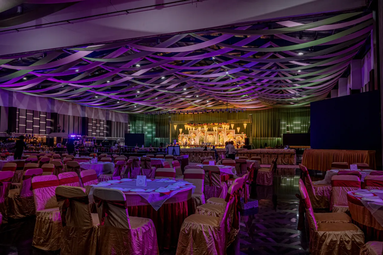 Air-conditioned hall arranged with round dining tables and a stage