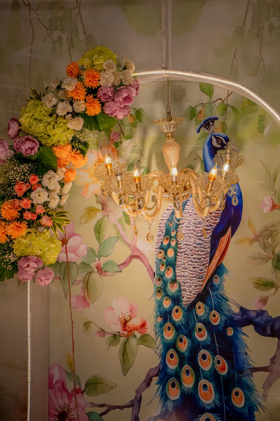 Peacock artwork, fresh florals and a crystal chandelier in the decorated hall